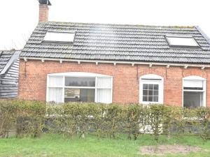 a red brick house with two windows and a fence at Holiday Home Nieuwvliet-Bad near Beach in Nieuwvliet-Bad