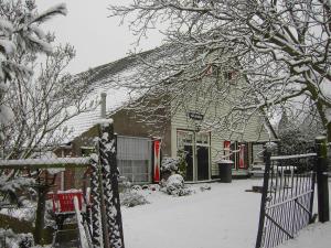 a house covered in snow in front of a fence at Cozy Holiday Home in Bergen op Zoom with Garden in Bergen op Zoom