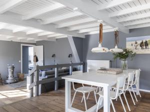 a dining room with a white table and chairs at Luxuriously restored farmhouse with trendy interior close to sea and forest in Groet