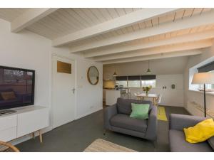 een woonkamer met een bank en een televisie bij Superb apartment near the beach in Vrouwenpolder in Vrouwenpolder