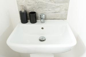 a white bathroom sink with two black bottles on it at Tranquil 1BR in Catford in London