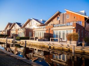 una fila di case vicino a un corpo d'acqua di Luxurious home with jetty, in a water-rich holiday park not far from Amsterdam a Uitgeest