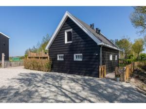 un granero negro con ventanas blancas y una valla en Family house with an ideal location private terrace garden and sauna, en Vrouwenpolder