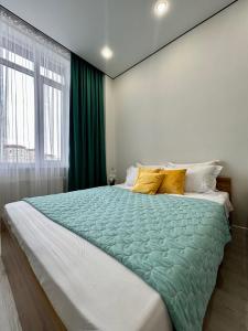 um quarto com uma cama grande e um edredão verde em 1-комнатная возле Посольства США и Мечети Хазрет Султан em Astana