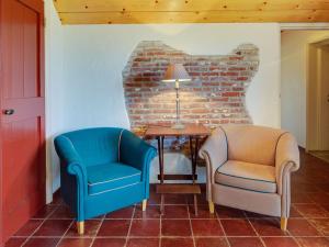dwa krzesła i stół w pokoju z ceglaną ścianą w obiekcie Cozy Apartment in Enschede near Forest w mieście Enschede