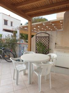 einen weißen Tisch und Stühle auf einer Terrasse in der Unterkunft Villetta Fiorita in San Vito lo Capo