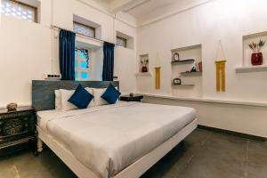 a bedroom with a large bed with blue pillows at Barefoot Boutique Hotel Udaipur in Udaipur