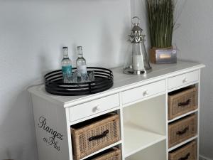 a white console table with plates and bottles on top at Hotel Restaurant Ostsee-Anker in Langballig
