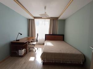 a bedroom with a bed and a desk and a window at Diplomat Apartment in Ulaanbaatar