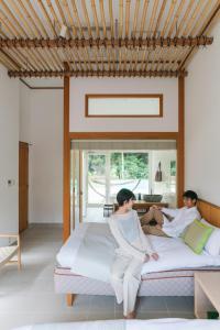 Un uomo e una donna seduti su un letto di コーラルテラス石垣島 a Fukai