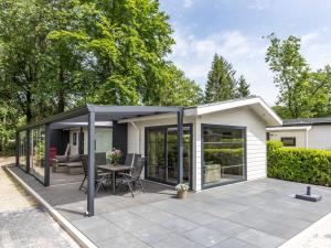 a pavilion with a table and chairs on a patio at Nice chalet with dishwasher, surrounded by forest in De Bult