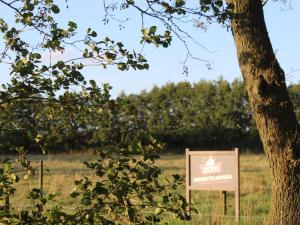 ein Schild auf einem Feld neben einem Baum in der Unterkunft Farmhouse in De Heurne near the forest in De Heurne
