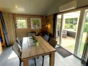 a dining room with a wooden table and chairs at Cozy tentlodge with roofed terrace in a green area in IJhorst