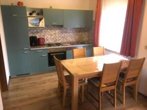 a kitchen with a wooden table and chairs and a kitchen with green cabinets at Ferienhaus-mit-Terrasse-und-grossem-Garten in Marktgraitz