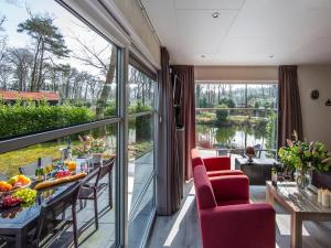 Habitación con mesa, sillas y ventana grande. en Modern chalet with two terraces and near a pond, en De Bult