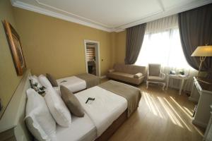 イスタンブールにあるビレック イスタンブール ホテルのベッド2台とソファが備わるホテルルームです。