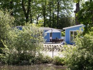 een blauw huisje in het bos met een tafel bij Beautiful house with sandy beach near Giethoorn in De Bult