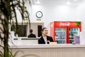 una mujer sentada en un mostrador en una tienda de cocacola en MILDOM Express, en Almaty