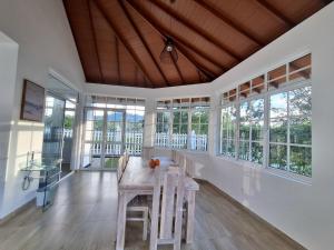 a dining room with a table and chairs and windows at OUNA Bungalow in Ella