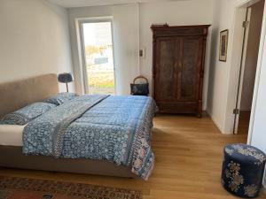 a bedroom with a bed with a blue blanket and a window at Allerinsel - Appartement am Celler Yachthafen in Celle