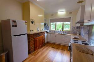 cocina con nevera blanca y suelo de madera en Elm Trees of Ross Cottage, en Ross