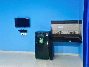a blue wall with a small refrigerator next to a desk at Hotel Downtown Calangute in Calangute