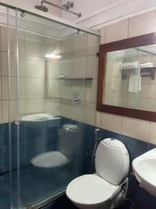 a bathroom with a toilet and a glass shower at Old Courtyard Hotel in Cochin