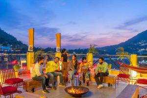 un grupo de personas sentadas alrededor de un fuego en una cubierta en The Hosteller Rishikesh, Ganges en Rishīkesh