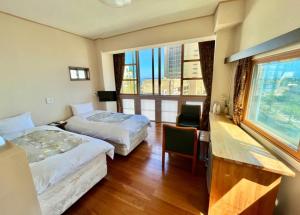 a hotel room with two beds and a desk and a window at Hostel and Cafe izu-no-umi in Atami