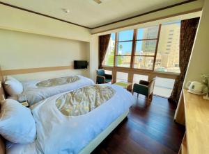 a hotel room with two beds and a window at Hostel and Cafe izu-no-umi in Atami