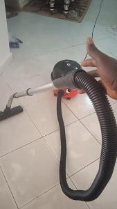 a person is holding a vacuum hose on the floor at 3 bedroom, free Wi-fi, Aircon & Hot water in Tujering