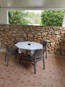 a table and chairs in front of a stone wall at Apartmani Vuković in Gajac