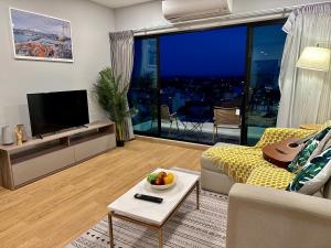 Una sala de estar con un sofá y un televisor. en Astra Sky River Paronama Pool Luxury Changklan Chiang Mai, en Chiang Mai