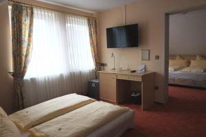 a hotel room with a bed and a desk and a television at Hotel & Restaurant Mainaublick in Uhldingen-Mühlhofen