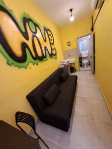 ein Wohnzimmer mit einer schwarzen Couch an einer gelben Wand in der Unterkunft Fellini Nine ground (talpiot) in Haifa