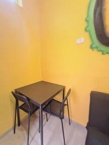 a table and chairs in a room with a yellow wall at Fellini Nine ground (talpiot) in Haifa