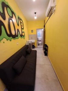 a living room with a black couch in a yellow wall at Fellini Nine ground (talpiot) in Haifa