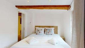 Schlafzimmer mit einem Bett mit weißer Bettwäsche und Kissen in der Unterkunft Résidence de l'ancien relais in Colmar