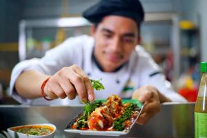 a man eating a plate of food in a restaurant at Paddyfield Inn in Mananthavady