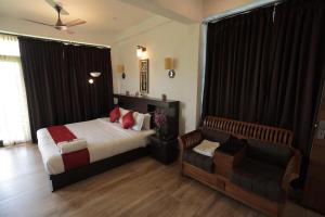 a bedroom with a bed and a couch at Paddyfield Inn in Mananthavady