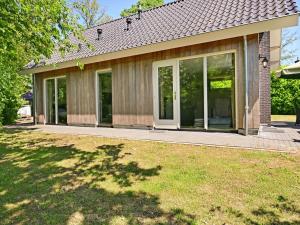 uma casa com portas de vidro deslizantes num quintal em Chalet with gorgeous view of the natural surroundings em Weerselo