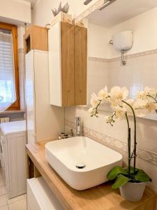 a bathroom with a white sink and flowers on a counter at La casa di Lory in Falconara Marittima