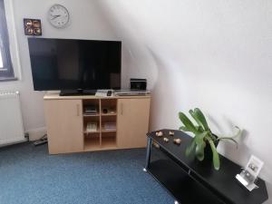 een woonkamer met een flatscreen-tv en een tafel bij Großes Gästezimmer mit Kühlschrank in Marbach am Neckar