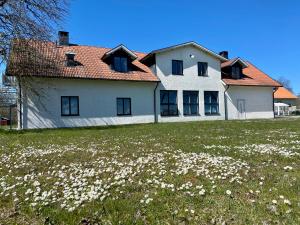 een groot wit huis met een bloemenveld bij Hangvar Skola Geografisalen in Lärbro