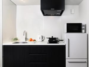 uma cozinha com armários pretos e um frigorífico branco em MIMARU TOKYO UENO INARICHO em Tóquio