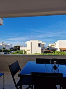 una mesa azul y sillas en un balcón con edificios en Dimora Carmela, en Torre Santa Sabina