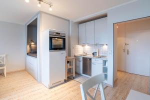 a kitchen with white cabinets and a white chair at Ferienwohnung Alkoven in Schilksee