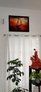 a plant in front of a window with a picture of a ship at Alleppy Whitefort Homestay Dulux Rooms -HouseBoat Available in Alleppey