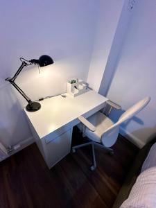een wit bureau met een lamp en een stoel bij Big Cozy Room near City Center in Dublin