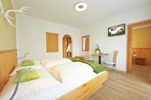 ein Schlafzimmer mit einem großen Bett mit weißer Bettwäsche und grünen Kissen in der Unterkunft Hotel Garni Landhaus Gitti in Zell am See
